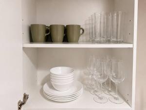 a shelf with plates and wine glasses on it at Modern North Van Escape with 2BR BBQ Workspace in North Vancouver