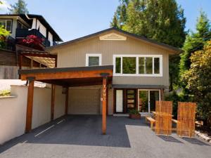 a house with a garage with two chairs in front of it at Modern North Van Escape with 2BR BBQ Workspace in North Vancouver