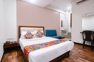 a bedroom with a large bed and a blue chair at FabHotel SK Galaxy in Thane
