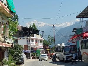 eine Stadtstraße mit Autos, einem Bus und einem Berg in der Unterkunft Devadidev Retreat in Gupta Kāshi