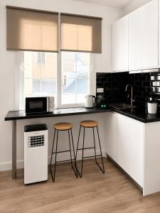 a kitchen with two stools and a counter with a microwave at Grand Central House - Classic Studio - GibraltarStay Apartments in Gibraltar