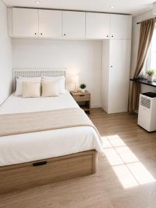 a bedroom with a large bed with white walls at Grand Central House - Classic Studio - GibraltarStay Apartments in Gibraltar