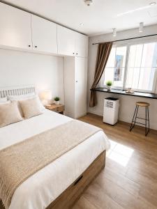a white bedroom with a large bed and a window at Grand Central House - Classic Studio - GibraltarStay Apartments in Gibraltar