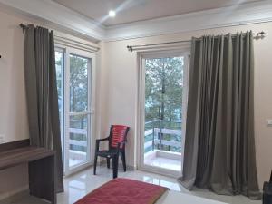 a room with a chair and a large window at Shivansh Hotel in Kānda