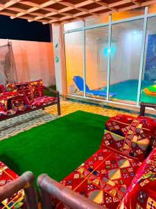 a living room with two couches and a green rug at شالية الرايس in Rayyis +2 photos