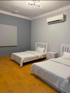 a room with two beds and a air conditioner at شالية الرايس in Rayyis