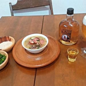 Eine Schüssel Suppe auf einem Holztisch mit einer Flasche Whisky. in der Unterkunft Camping 4m in Aiuruoca