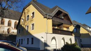 a yellow and white building with a balcony at Apartment.Kirche in Sankt Georgen ob Murau
