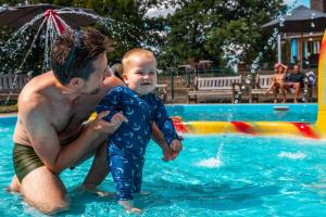a man holding a baby in a swimming pool at Vakantiepark Witterzomer Assen in Assen
