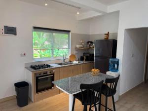 a kitchen with a table and a sink and a refrigerator at Blissful hill top Apartment in Praslin