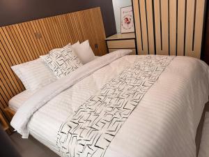 a bedroom with a white bed with a wooden headboard at Elite Apartments Masaka in Kigali
