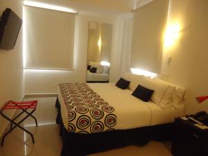 ein Hotelzimmer mit einem Bett mit weißer Bettwäsche und Kissen in der Unterkunft Zalmedina Hotel in Cartagena de Indias