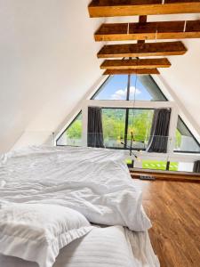 a white bed in a room with a large window at CBN Cabana in Muntele Cacovei