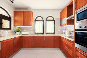 a large kitchen with wooden cabinets and appliances at Casa Sem Pressa - Beach, Pool & Central Carvoeiro in Carvoeiro