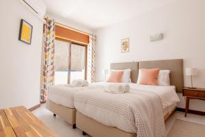 a bedroom with a large bed with two towels at Casa Sem Pressa - Beach, Pool & Central Carvoeiro in Carvoeiro
