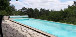 a swimming pool on a patio with trees in the background at Suite Maraval Chez L'habitant in Trélissac