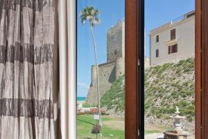 a window with a view of a castle and a palm tree at Iamartino Quality Rooms in Termoli