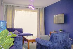 a living room with two blue chairs and a table at Hidden Gems Homes Modern 2BR Near JKIA, Athi River in Athi River