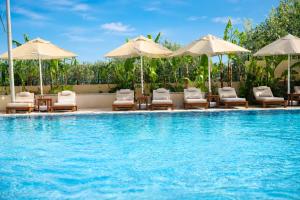 ein Schwimmbad mit Liegestühlen und Sonnenschirmen in der Unterkunft Kamer Exclusive Hotel & Suites in Cesme