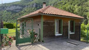 a small wooden house with a mountain in the background at Maison au bord de l'eau avec Jacuzzi in Millau