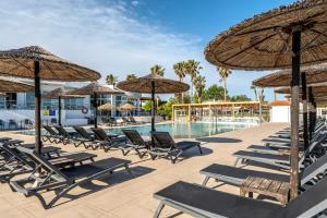 a group of chairs and umbrellas next to a swimming pool at Akti Dimis Hotel in Tigaki