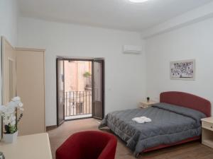 a bedroom with a bed and a red chair at B&B La Via dei Mulini in Corigliano Calabro