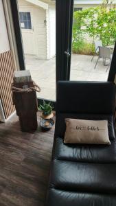 a black leather couch with a pillow on a porch at Bos & Bubbels Chalet in Epe