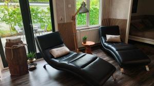 a living room with two leather chairs and a table at Bos & Bubbels Chalet in Epe