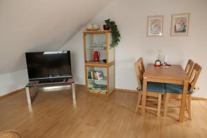 ein Wohnzimmer mit einem Tisch und einem TV sowie einem Tisch und Stühlen in der Unterkunft Ferienwohnung Max-und-Moritz in Flensburg