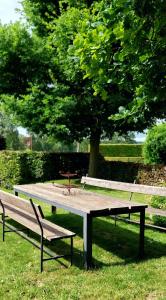 a picnic table in a park with two benches at B&B Het Hof van Petronilla in Gooik