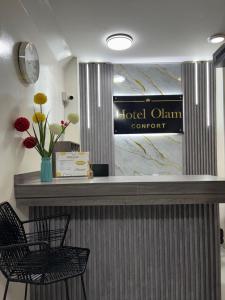 a hotel claim counter with two chairs and a vase of flowers at Hotel Olam Confort in Villavicencio