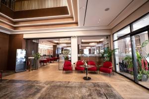 eine Lobby mit roten Stühlen und Tischen in einem Gebäude in der Unterkunft Hotel Mozart in Shkodra