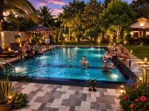 a group of people sitting in a swimming pool at night at Nature Lounge in Udawalawe