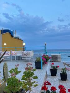 a patio with flowers on the beach next to the ocean at British Hotel in Himare