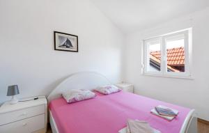 a white bedroom with a pink bed and a window at Apartments Bašić Pirovac - Sea view - Small and large groups in Pirovac