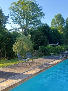 two chairs sitting on a deck next to a swimming pool at La Feuilleraie in Tours