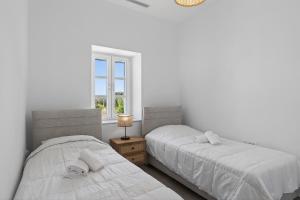two beds in a bedroom with a window at Celeste Syros Retreat in Vári