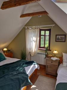 a attic bedroom with two beds and a window at Chata pod Mogielicą - klimatyczny dom na wyłączność z ogrodem i widokiem na góry in Słopnice