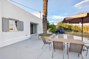 a patio with a table and chairs and an umbrella at Celeste Syros Retreat in Vári
