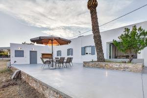 a patio with a table and a palm tree at Celeste Syros Retreat in Vári