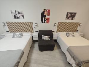 a room with two beds and a chair in it at AniCa IV De Cine in Tomelloso +23 photos