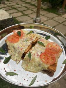 a plate of food with bread and tomatoes on it at Laughing Leopard Hostel in Nuwara Eliya