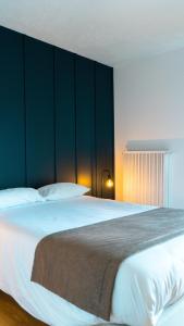 a bedroom with a large white bed with a green wall at Auberge Du Roselet in Duingt