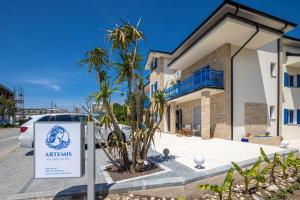 a sign in front of a house with a palm tree at Artemis Escape Suites Srebrno Jezero in Veliko Gradište