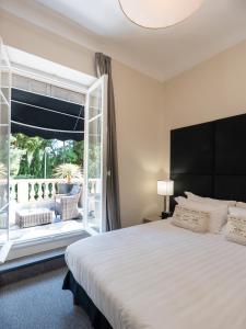 ein Schlafzimmer mit einem großen Bett und einem großen Fenster in der Unterkunft Hotel De Monaco in Cap d'Ail