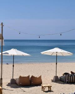 two umbrellas and chairs on a beach with the ocean at Anda Lanta Resort in Ko Lanta