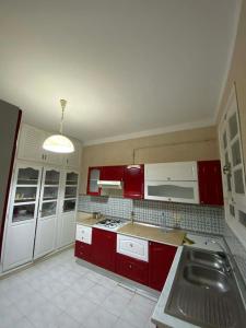 a kitchen with red cabinets and a sink at Cozy Appartement Mahdia in Mahdia