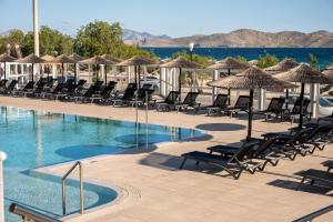 a swimming pool with lounge chairs and umbrellas at Akti Dimis Hotel in Tigaki