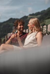 a man and a woman holding a glass of wine at Genusshotel Fichtenhof in Grossarl