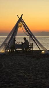 two people sitting at a table under a tent on the beach at Anda Lanta Resort in Ko Lanta